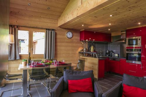 une cuisine avec des armoires rouges et une table avec des chaises dans l'établissement Chalet Pesse, à Manigod