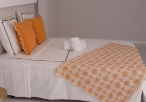 a bed with orange and white pillows on it at Résidence Cazino Apartamentos in Praia