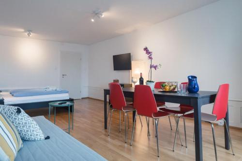 a living room with a dining room table and red chairs at HITrental Chapel Bridge Apartments in Luzern