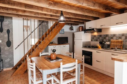une cuisine avec une table en bois, des chaises et un escalier dans l'établissement Le Logis Du Prieure, à Les Châtelliers-Châteaumur