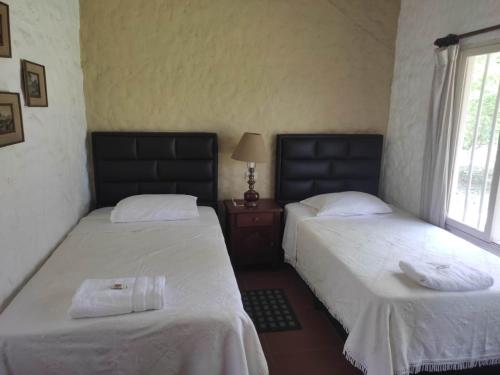 a bedroom with two beds and a table with a lamp at Cabanas Descarpontriez in Buena Vista