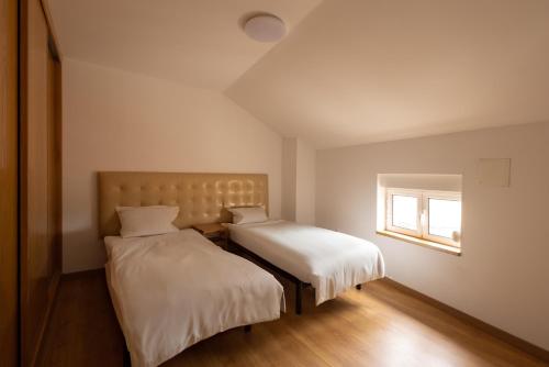 two beds in a small room with a window at Casa Amarela - Serra da Estrela Portugal in Verdelhos