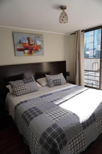 a bedroom with a large bed with a checkered blanket at San Ignacio Suite Apartments in Santiago
