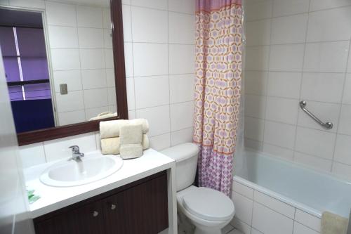 a bathroom with a toilet and a sink and a tub at San Ignacio Suite Apartments in Santiago