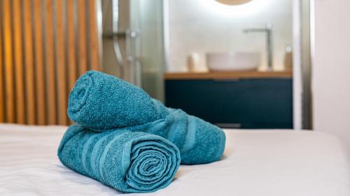 une serviette bleue posée sur un lit dans l'établissement Le Chouette Toucan, à Dijon