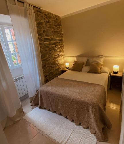 a bedroom with a bed and a stone wall at Alojamiento Virita in Nigrán