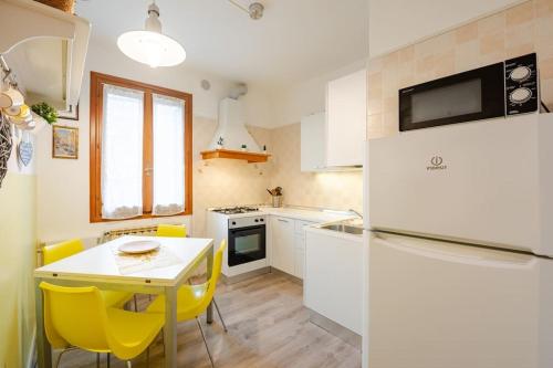 eine kleine Küche mit einem Tisch und gelben Stühlen in der Unterkunft Lovely House Claudia-perfetto per Venezia in Mestre
