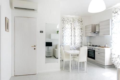 a white kitchen with a table and white chairs at C004 - Camerano, nuovo bilocale con aria condizionata in Camerano