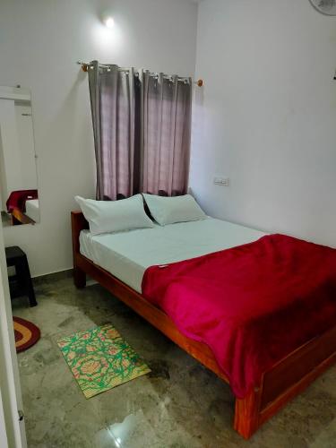 a bedroom with a bed with a red blanket on it at Giridhama homestay in Chikmagalūr