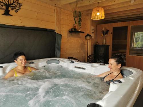 two people sitting in a hot tub in a room at Gîtes ETCHE ARGUINIA in Montory