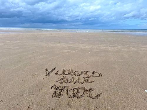 a sign written in the sand on a beach at Super Deauville appartement 2 pièces cosy proche plage plein sud in Villers-sur-Mer