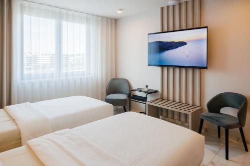 科佩尔Hotel Capris Capodistria Boutique的一间有两张床和一台平板电视的酒店房间