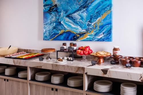 a buffet with dishes and a painting on the wall at Hotel Capris Capodistria Boutique in Koper
