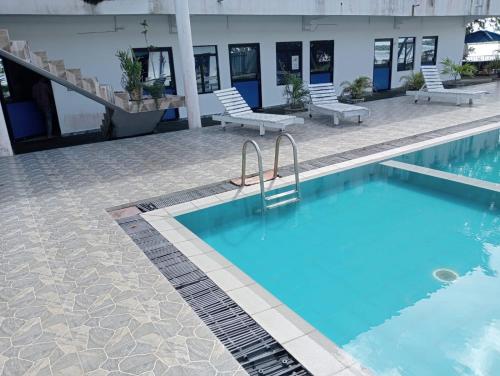 a swimming pool with two chairs next to a building at Treatooo Lake resort in Batticaloa