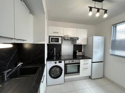 une cuisine avec des armoires blanches et une laveuse et une sécheuse dans l'établissement Le Repaire de Mickey, à Chessy