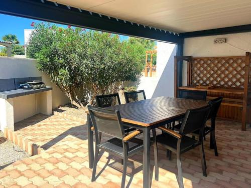 une table et des chaises en bois sur une terrasse dans l'établissement Charmante maison climatisée 6 personnes proximité plage, à Frontignan