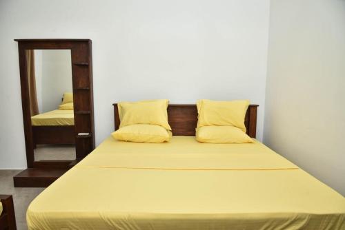 a bedroom with a bed with yellow pillows and a mirror at Travel Neth Holidays Bungalow Anuradhapuraya in Anuradhapura