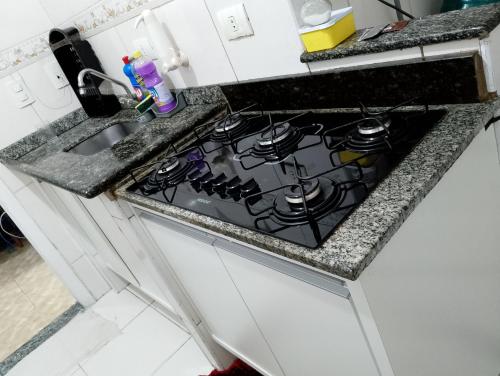 a kitchen counter with a stove and a sink at Apto Domeni, seu conforto a 10 min da praia! in Praia Grande