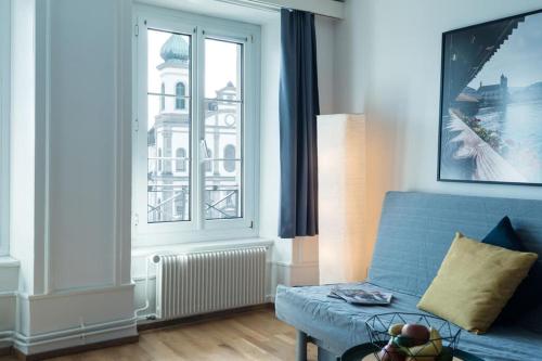 a living room with a blue couch and a window at HITrental Chapel Bridge Apartments in Luzern