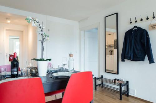 a dining room table with red chairs and a mirror at HITrental Chapel Bridge Apartments in Luzern