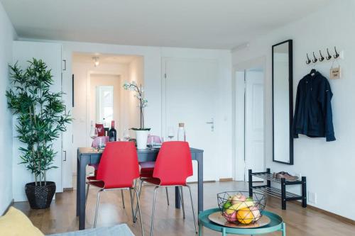 a dining room with red chairs and a table at HITrental Chapel Bridge Apartments in Luzern