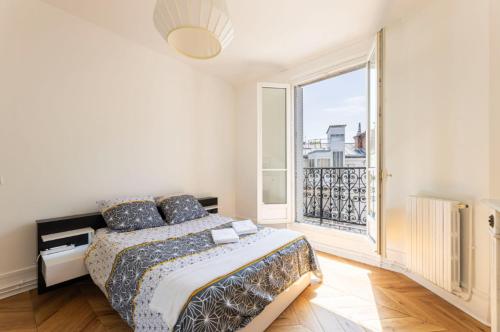 une chambre avec un lit et une grande fenêtre dans l'établissement Vue Tour Eiffel et 5 minutes des Champs-Elysees Appartement 2 chambres Paris 16 Etoile, à Paris
