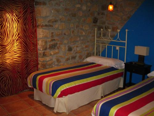 a bedroom with two beds and a stone wall at Hotel La Pradera de Marta in Quintanaentello