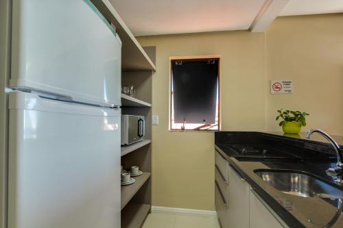 a kitchen with a refrigerator and a sink at Flat Pietra in Florianópolis