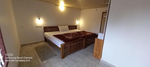a small bedroom with a bed and a table at Perumaal Homestay in Munnar