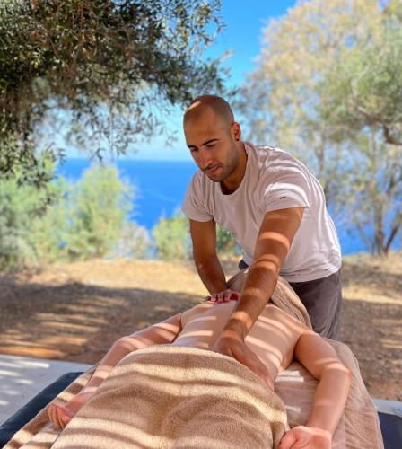 a man is on top of a bed at Maison Meltem in Agia Pelagia