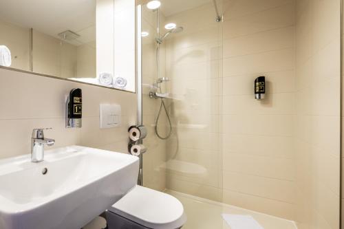 a bathroom with a sink and a toilet and a shower at Serways Hotel Feucht Ost in Feucht