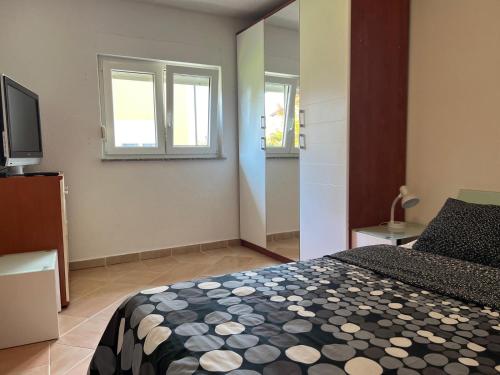 a bedroom with a bed and two windows and a television at Minihaus in Zagreb in Sesvete