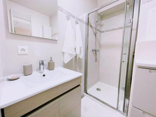 une salle de bain blanche avec une douche et un lavabo dans l'établissement Cosy Studio Balcon Paris&Disney, à Noisy-le-Grand