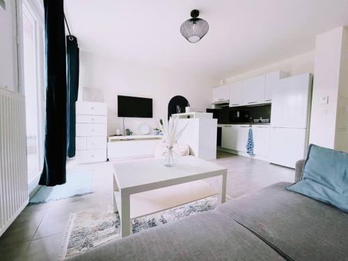 un salon blanc avec une table et un canapé dans l'établissement Cosy Studio Balcon Paris&Disney, à Noisy-le-Grand