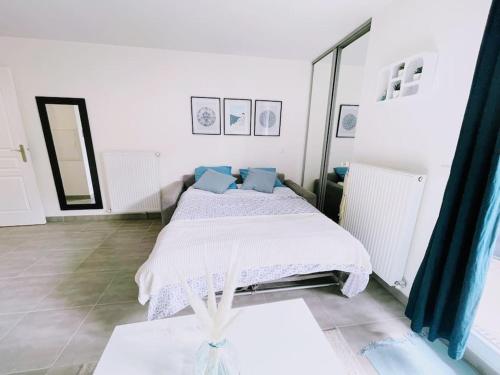 - une chambre blanche avec un lit et des oreillers bleus dans l'établissement Cosy Studio Balcon Paris&Disney, à Noisy-le-Grand
