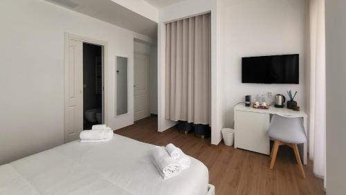 a white bedroom with a bed and a desk and a television at Latte e Letto in Avellino