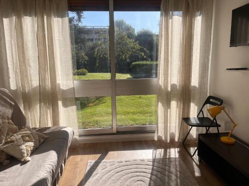 un salon avec une grande fenêtre et un canapé dans l'établissement Vue Jardin, à Le Chesnay