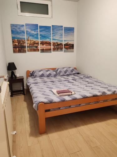 a bed in a room with four paintings on the wall at Cozy green house (free parking spot) in Belgrade