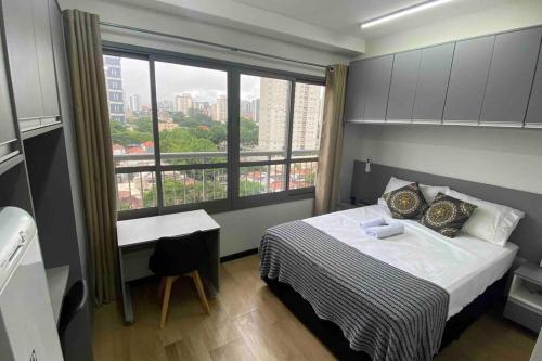 圣保罗Apartamento Studio Vila Mariana的一间卧室，里面有一张床和一扇大窗户。
