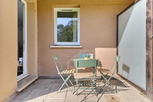 une table et des chaises assises sur une terrasse dans l'établissement Appartement Bleu Turquoise - Welkeys, à Équemauville