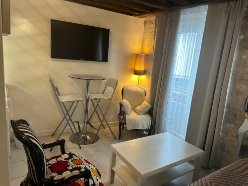 - un salon avec une table, des chaises et une télévision dans l'établissement Cosy studio Montorgueil, à Paris