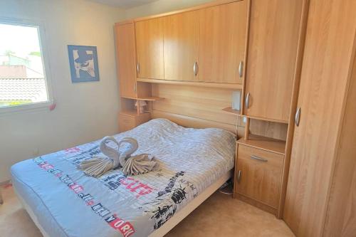 - une petite chambre avec un lit et des placards en bois dans l'établissement La Malou, à Portiragnes