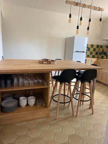 a kitchen with a wooden table and stools at Villa Kéana en Sud Ardèche, avec piscine in Lachapelle Sous Aubenas