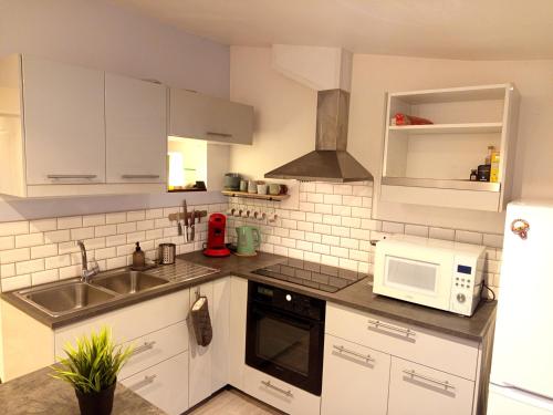 a kitchen with white cabinets and a sink and a microwave at Escale - Maison - Nantes aéroport in Bouguenais