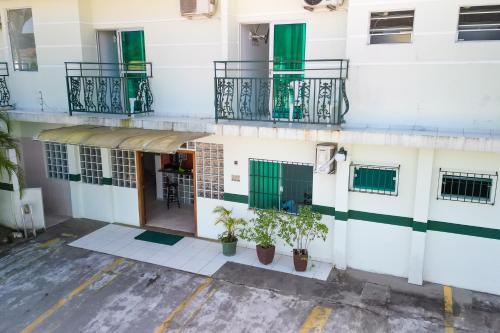 an apartment building with green windows and potted plants at VELINN Pousada Entre Praias in Ubatuba
