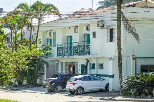 two cars parked in front of a white house at VELINN Pousada Entre Praias in Ubatuba