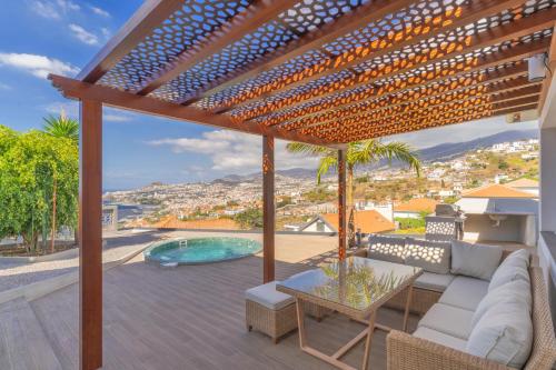 a patio with a couch and a table and a pool at Casa Trollis by Holiday Rental Madeira in Funchal