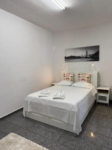 een witte slaapkamer met een groot wit bed en 2 tafels bij B&B Ilien in Bellinzona