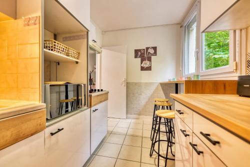 a kitchen with white cabinets and a counter and stools at Appartement familial et cozy - Wifi - Espace Travail- Parking in Mérignac