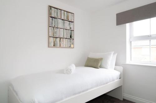 a white bedroom with a book shelf on the wall at The Voyager - Newly Furnished Home in Derby